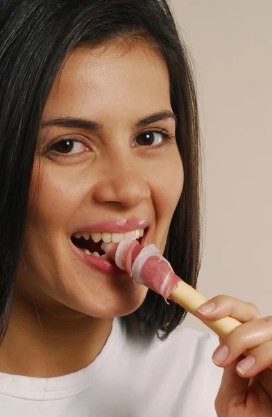 Jovem mulher comendo prosciutto crudo e grissini — Fotografia de Stock