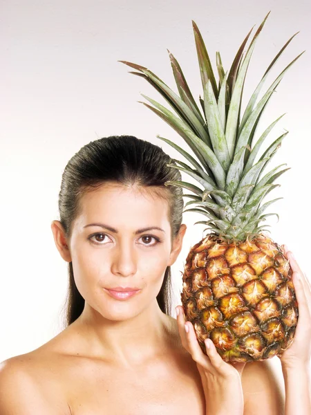 年轻女子在白色背景上举行一个菠萝 — 图库照片