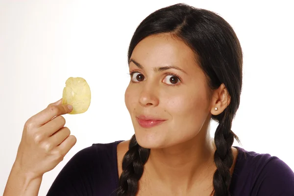 Mulher latina segurando um chip de batata à vela. Mulher comendo batata frita — Fotografia de Stock