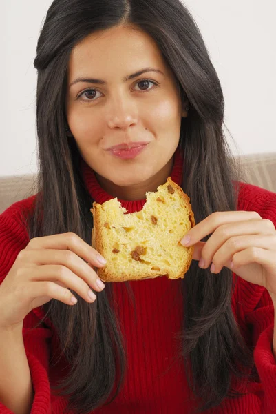 Mujer joven comiendo un pan fresco. Mujer joven comiendo panettone —  Fotos de Stock