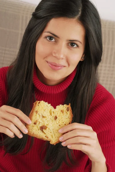 Giovane donna che mangia un pane fresco. Giovane donna che mangia panettone — Foto Stock