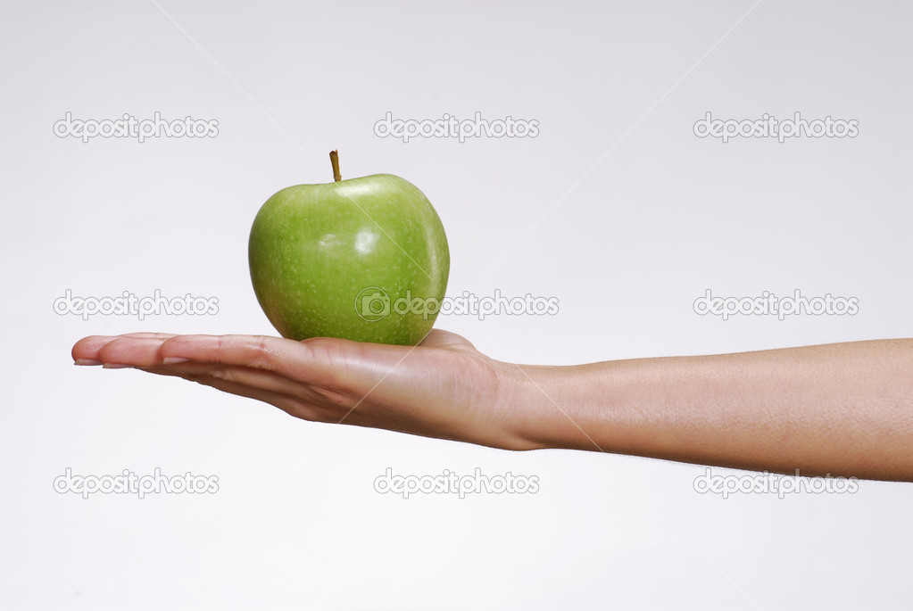 Female hand holding a green apple.