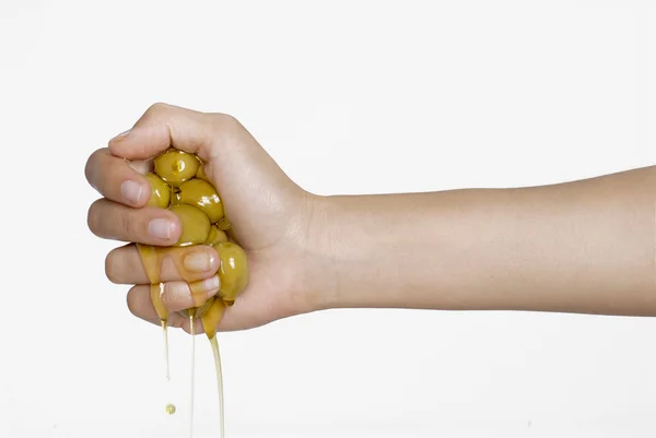 A hand presses olives .Olive oil pouring from olive — Stock Photo, Image