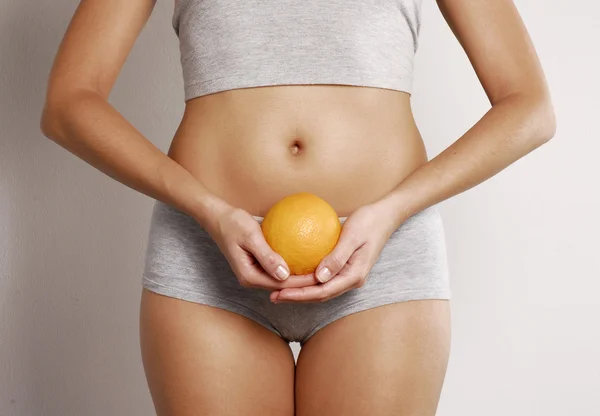 Jovem mulher corpo detalhe segurando uma laranja — Fotografia de Stock