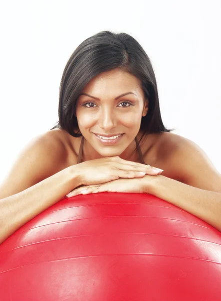 Junge lateinische Frau hält einen roten Ball im Fitnessstudio. — Stockfoto