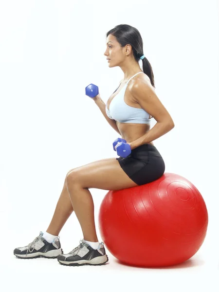 Junge Frau macht Fitnesstraining mit rotem Ball. Stockbild