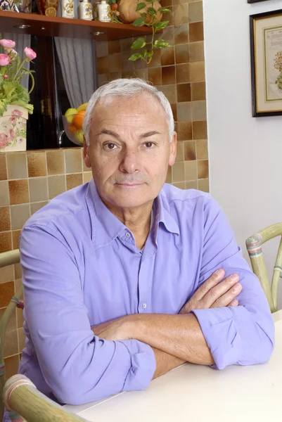 Senior man portret zit in een keuken. — Stockfoto