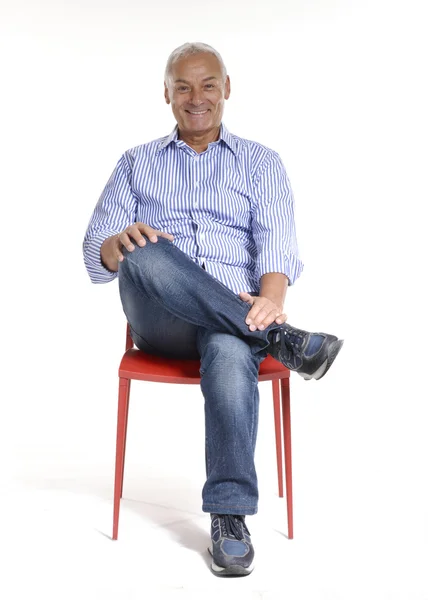 Portrait of a casual senior sitting on a chair on white background. — Stock Photo, Image