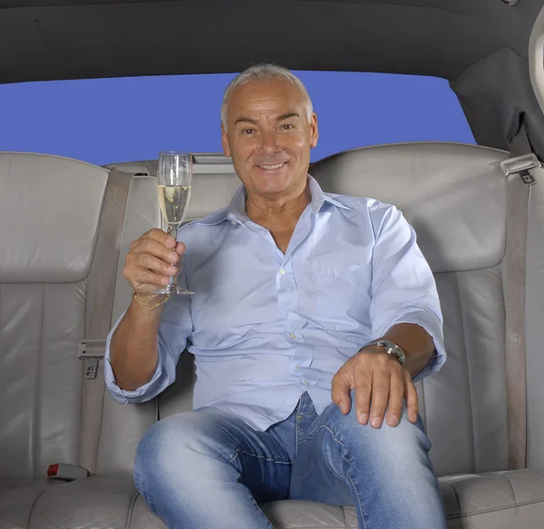 Heureux homme âgé buvant du champagne dans une limousine . — Photo