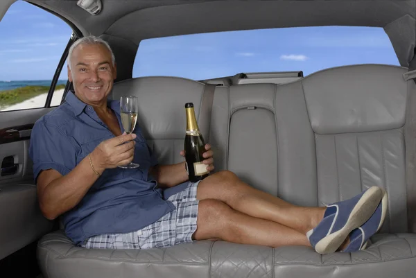 Heureux homme âgé buvant du champagne dans une limousine . — Photo