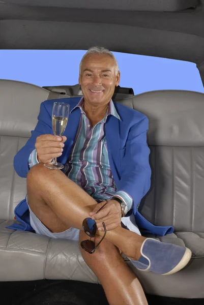 Lycklig senior man dricka champagne inuti en limousine. — Stockfoto