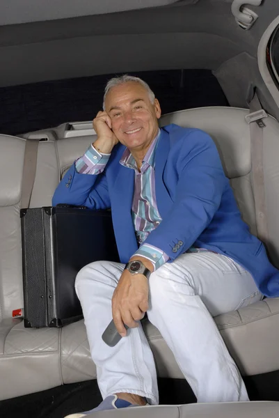 Succesvolle senior zakenman in een auto met een telefoon. — Stockfoto