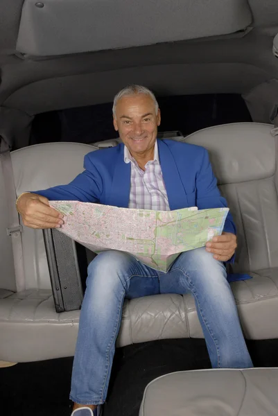 Senior man in een limousine houden een kaart. — Stockfoto