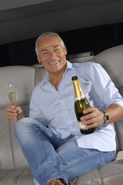 快乐的高级人喝香槟里面一辆豪华轿车. — 图库照片
