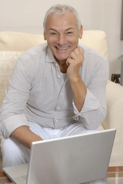 Sorrindo idoso idoso com laptop em casa — Fotografia de Stock