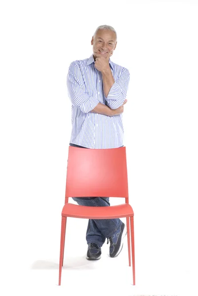 Äldre man med en röd stol på vit bakgrund. — Stockfoto