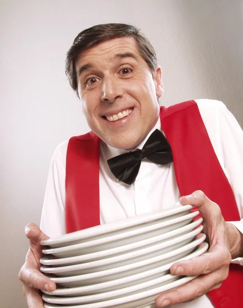 Χαρούμενος σερβιτόρος κρατώντας πιάτα σε άσπρο φόντο. — Φωτογραφία Αρχείου