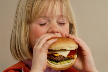 Hamburger yiyen küçük kız.