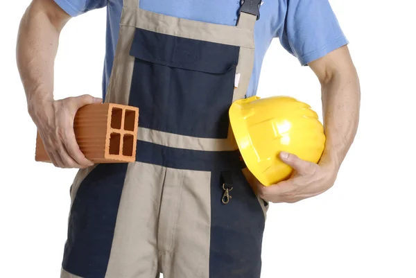 Obrero de la construcción sosteniendo un casco amarillo y ladrillo . — Foto de Stock
