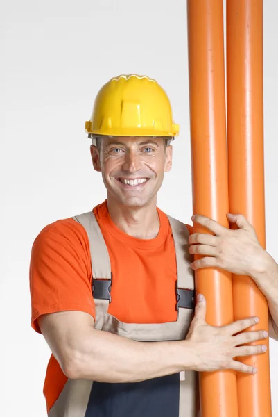 Encanador segurando dois tubos de plástico laranja — Fotografia de Stock
