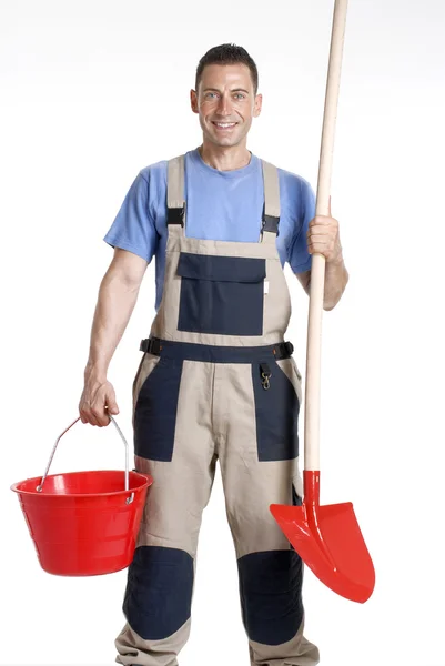 Trabajador sosteniendo un cubo rojo y una pala sobre fondo blanco . — Foto de Stock