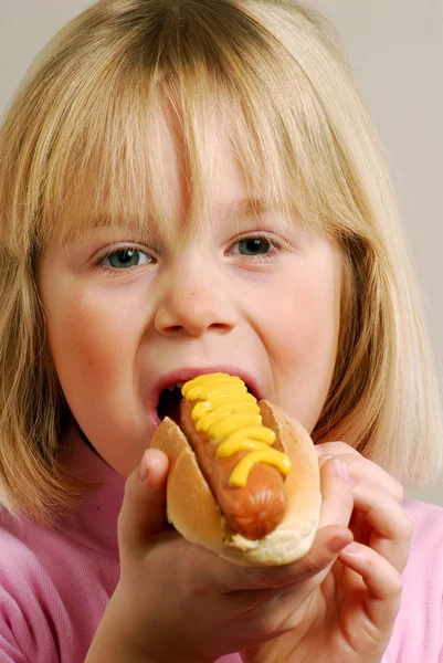 Liten flicka äter en varm dog.kid äta varmkorv. — Stockfoto