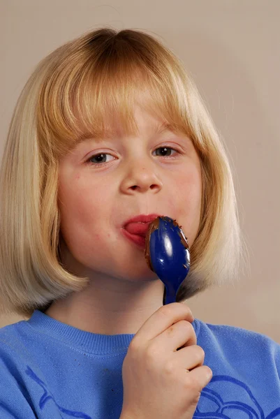 Liten flicka äter choklad grädde — Stockfoto