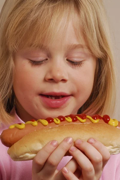 Little girl eating a hot dog — Zdjęcie stockowe