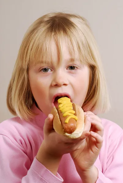 Lilla flickan äta en varmkorv — Stockfoto