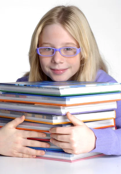 Schulmädchenporträt hinter Büchern. — Stockfoto