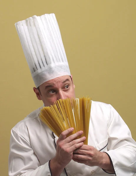 Jonge chef-kok houden een bord pasta. — Stockfoto