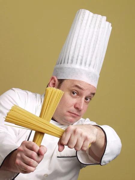 Jonge chef-kok houden een bord pasta. — Stockfoto