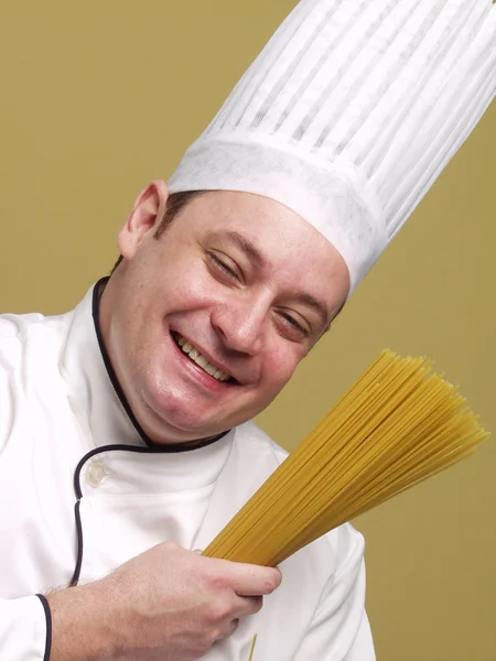Jonge chef-kok houden een bord pasta. — Stockfoto