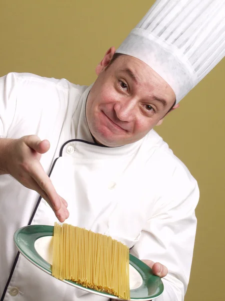 Joven chef sosteniendo un plato de pasta . — Foto de Stock