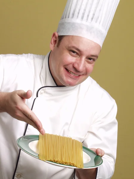 Joven chef sosteniendo un plato de pasta . —  Fotos de Stock