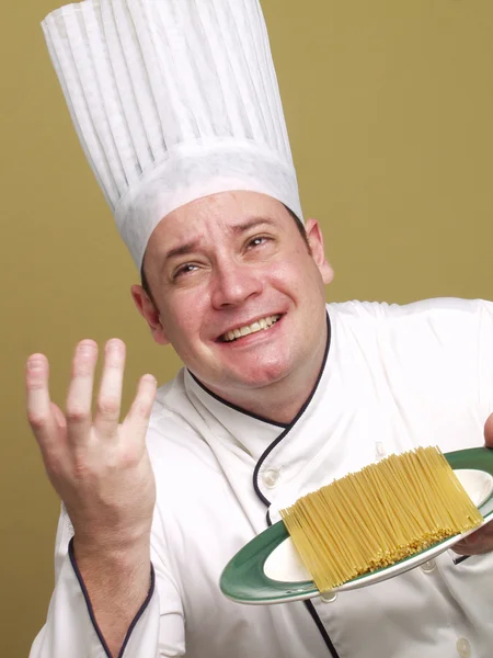 Joven chef sosteniendo un plato de pasta . — Foto de Stock