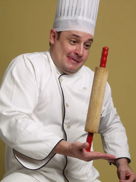 Jeune chef jongle avec un rouleau à pâtisserie sur fond jaune . — Photo