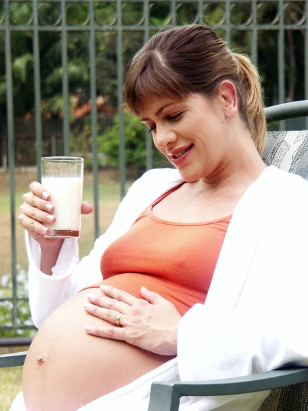 Jeune femme enceinte boire du lait en plein air — Photo