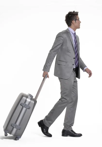 Jonge zakenman wandelen en trekken zijn bagage. — Stockfoto