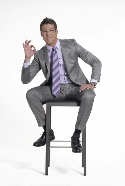Junger Geschäftsmann sitzt auf einem Stuhl auf weißem Hintergrund. — Stockfoto