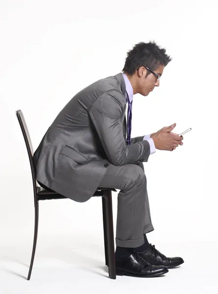Bir sandalyede oturan ve bir cep telefonu kullanarak genç işadamı. — Stok fotoğraf