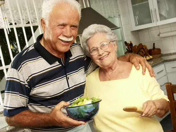 Gelukkige senior paar voorbereiding van plantaardige salade in de keuken. grootouders op keuken bereiden plantaardige salade. — Stockfoto