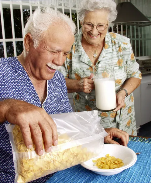 Dziadkowie jeść płatki kukurydziane zbóż w kuchni. — Zdjęcie stockowe