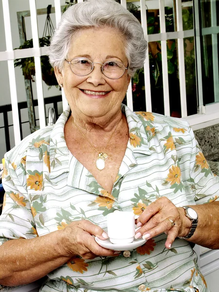 Grand mother drinking coffee in a kitchen.