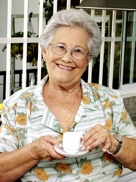 Grand mother drinking coffee in a kitchen. — Stock Photo, Image