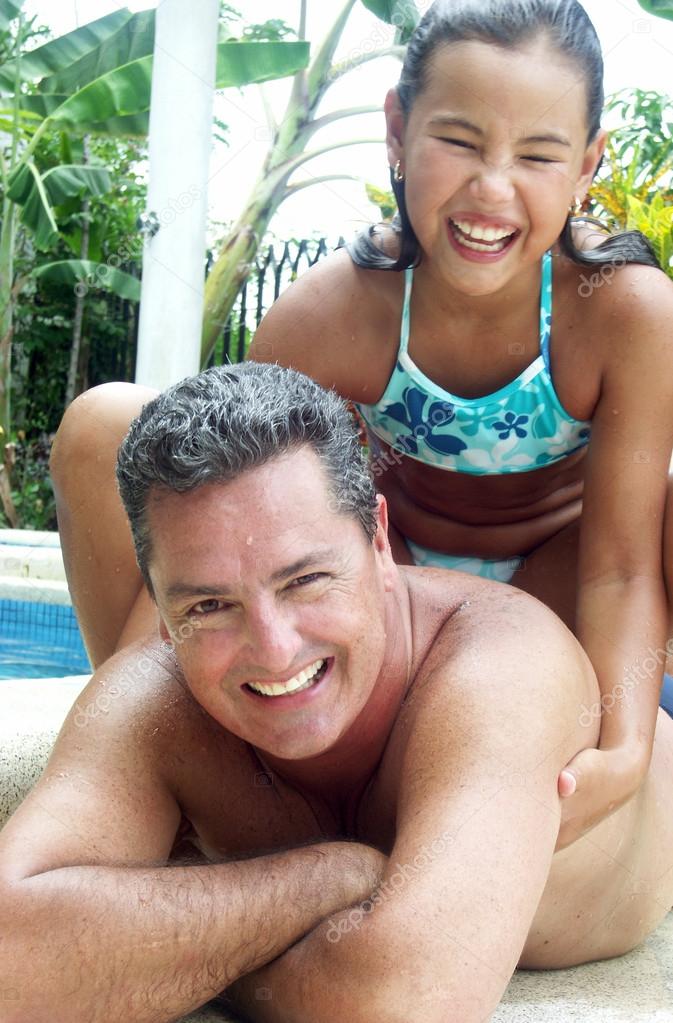 Hispanic father and daughter enjoying a swimming pool.