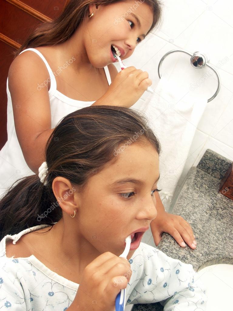 Two girls brushing their teeth.
