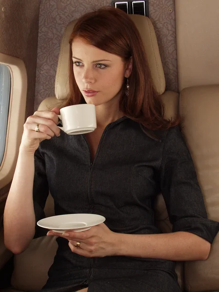 Geschäftsfrau trinkt Kaffee im Privatflugzeug. — Stockfoto