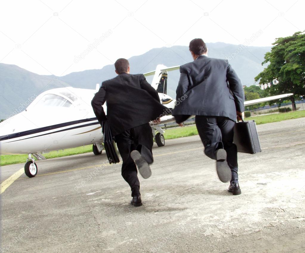 Two businessman running towards a plane