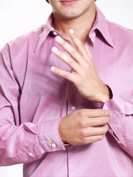 Joven hombre hispano abotonándose la camisa sobre fondo blanco . — Foto de Stock